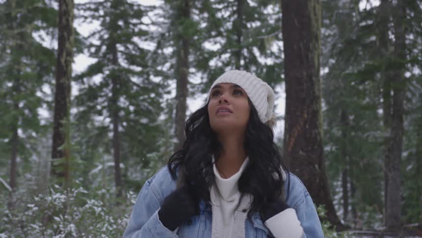 Young woman looks around in the winter forest