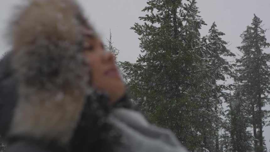 A woman turns her face up towards the falling snow