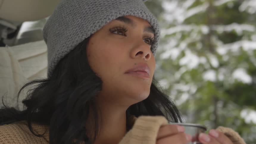 A woman sips from a metal mug sitting outside