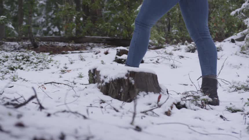 A woman walking through the snow in a forest