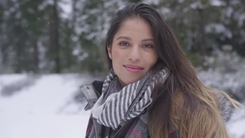 Young woman turns to look at camera in snowy forest