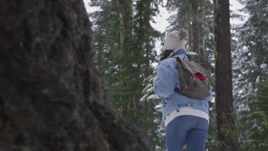 A black woman walks through a snowy forest