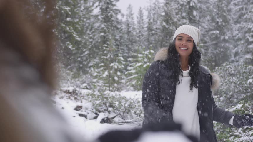 A woman laughs and throws a snowball