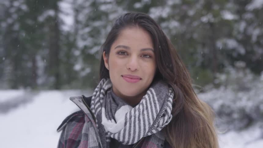 A woman stands outside in the snow and smiles