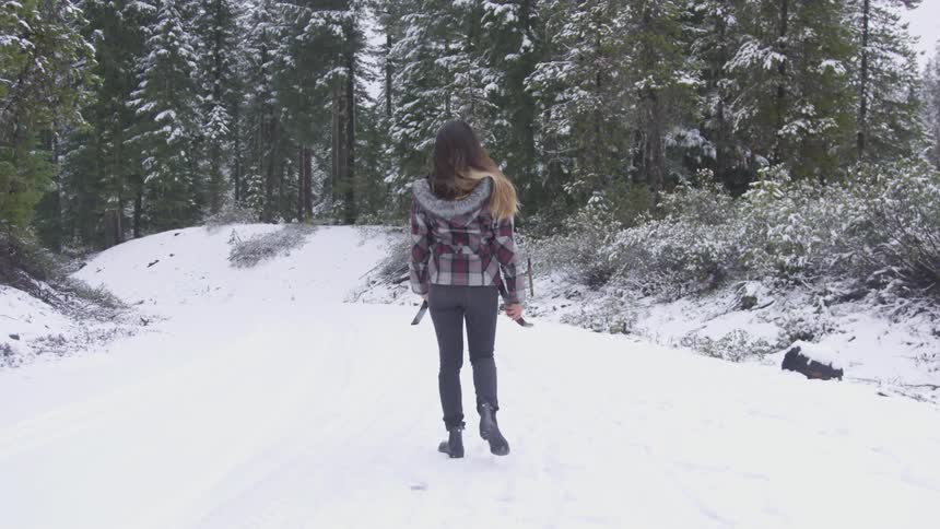 A young girl walks through a snow covered forest