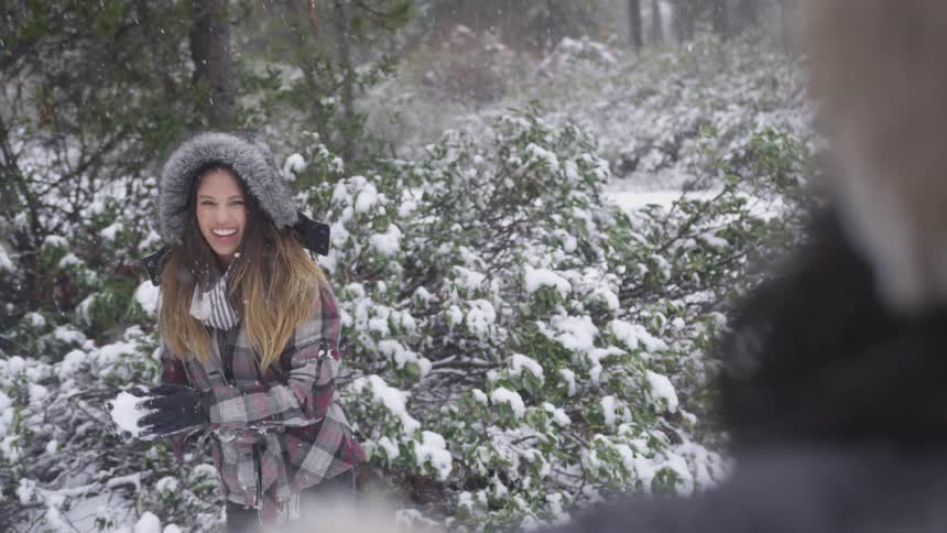 A young woman throws a snowball at her friend