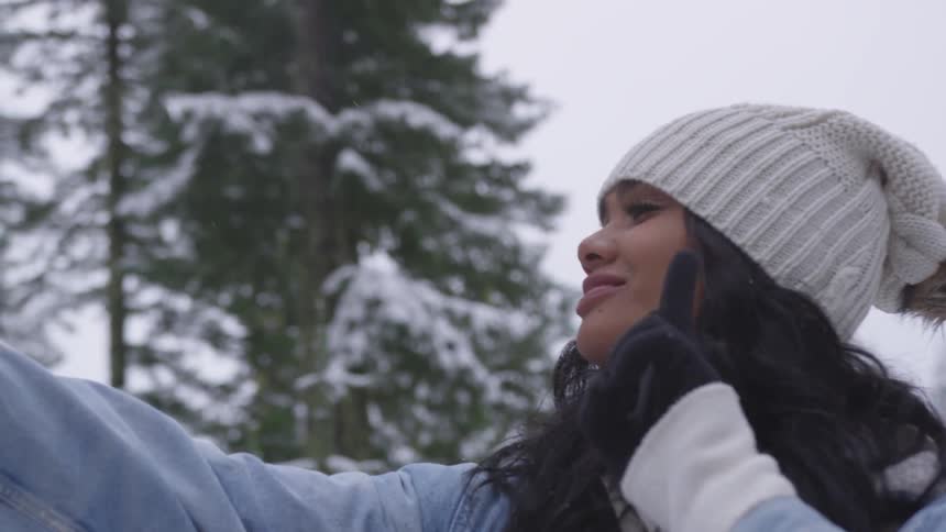 Young woman gives peace sign while taking selfie in snow