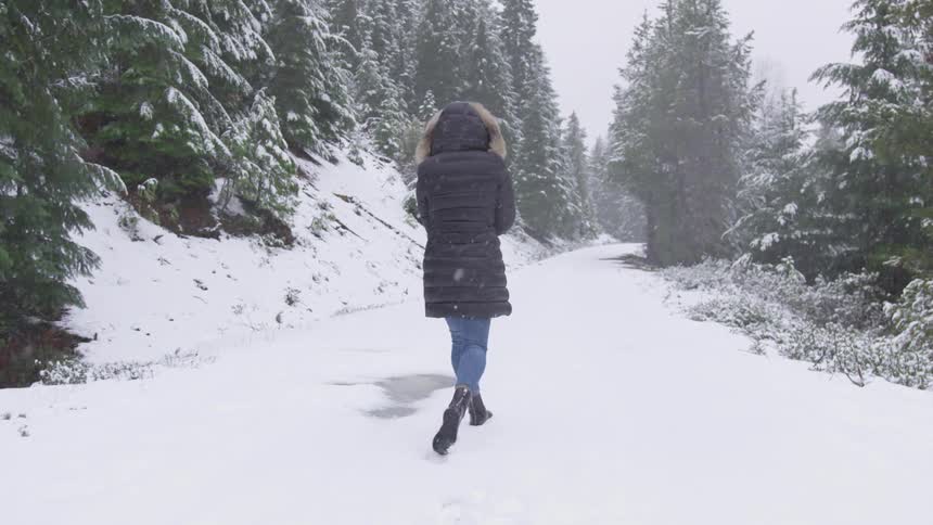 A woman is walking in the snow