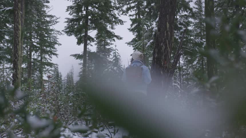 A woman standing in a forest full of snow