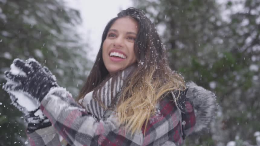 Brunette woman gets down to take snowball and then throws it when it snows