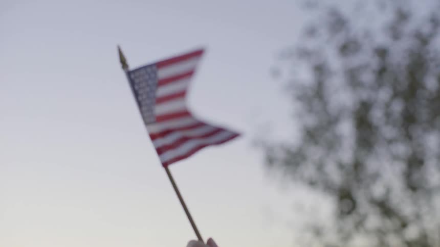A person waves a small american flag
