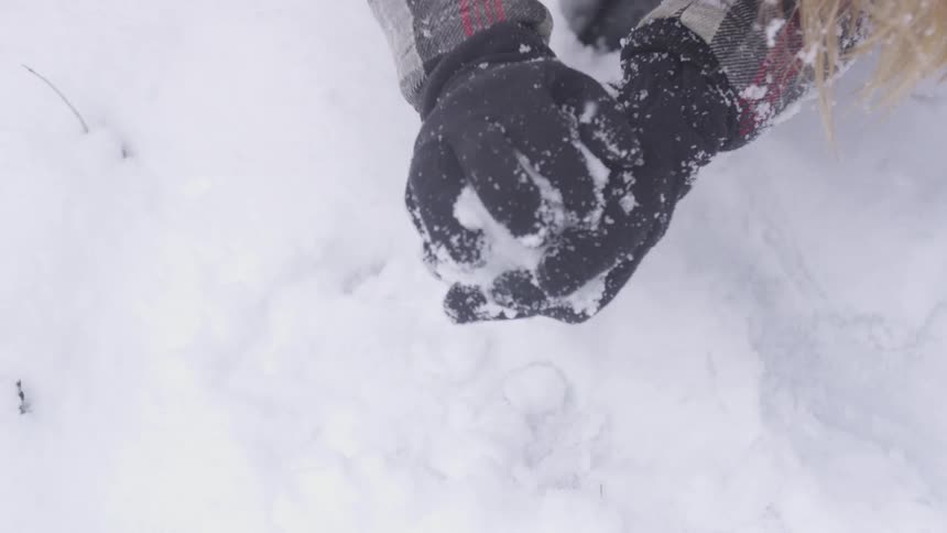 Woman gathers snow into snowball