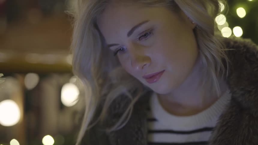 A woman's face is illuminated by a screen