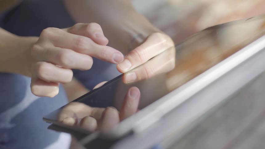 Woman uses tablet indoors when the sun shines on her hands