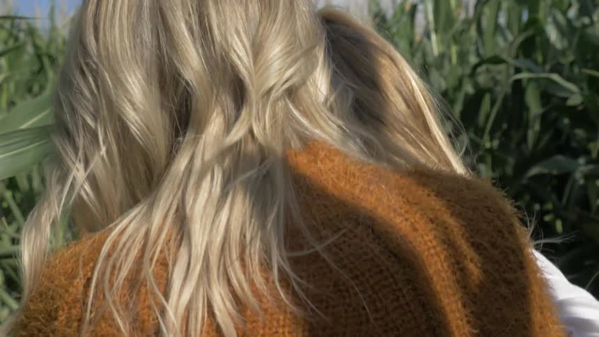 Mother and daughter walking down rows of corn