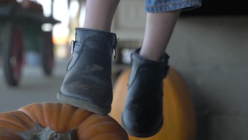 A child stands on a pumpkin