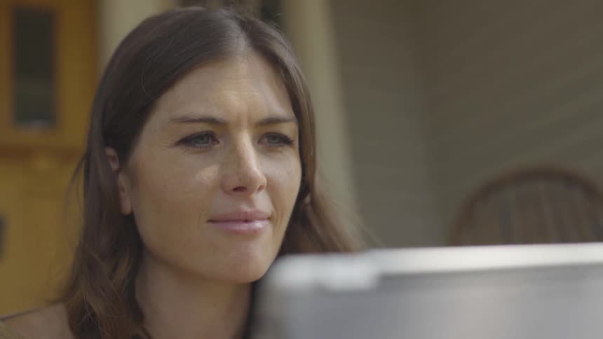A white woman looks confused as reads something on a monitor