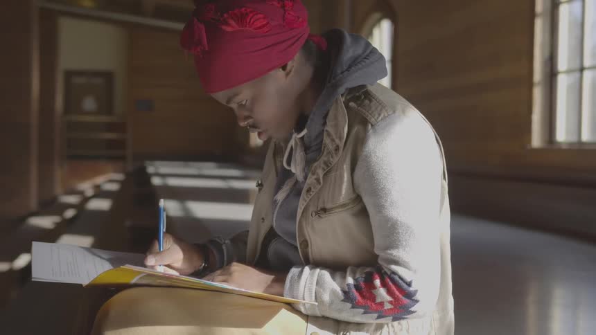 A girl works on homework in an empty classroom