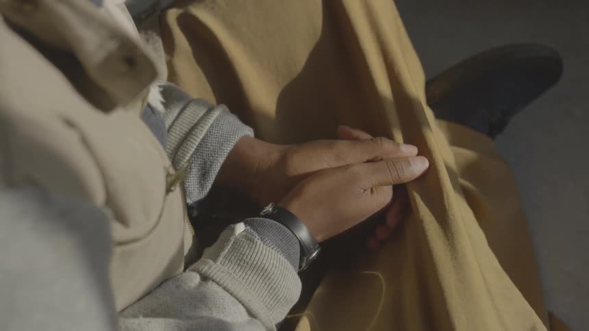 Person is sitting with their legs crossed and hands together