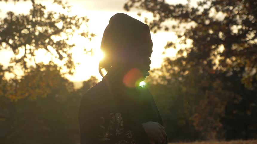 A woman is talking outside with her eyes closed