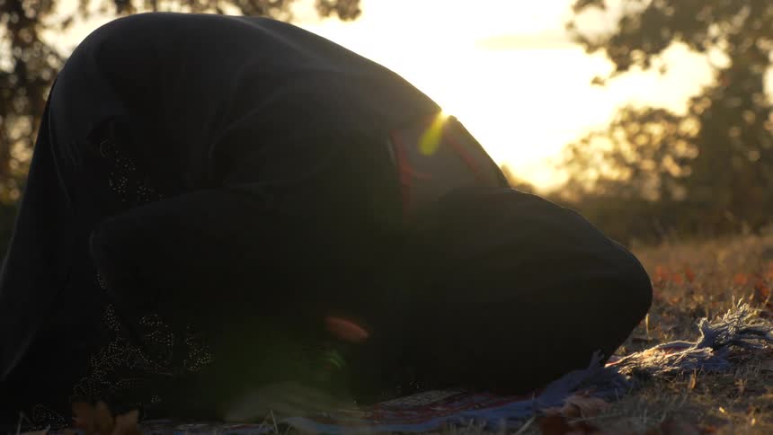 Woman praying outside at sunset