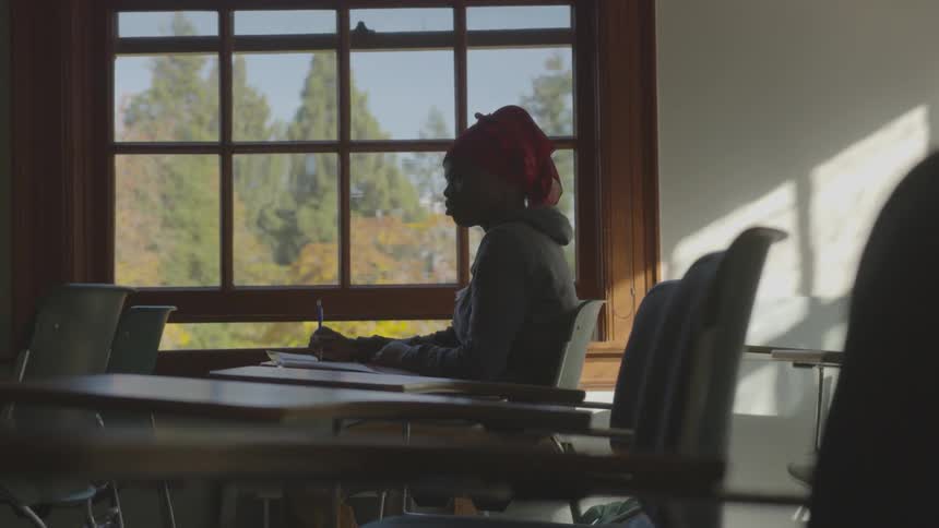 Woman sits in dark classroom