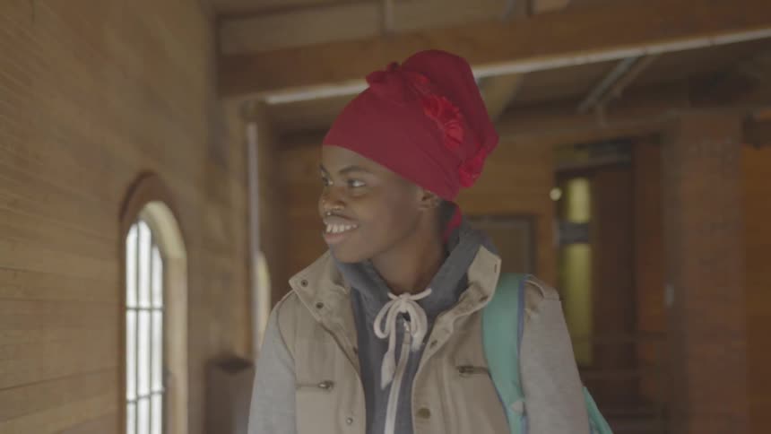 A woman is walking and smiling in the hall
