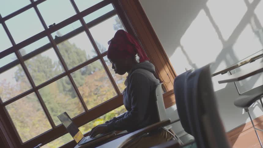 A girl types on a laptop while sitting at her desk