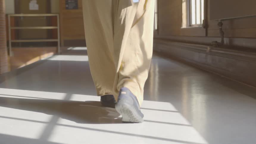A persons wearing baggy pants in walking down a hallway inside a building