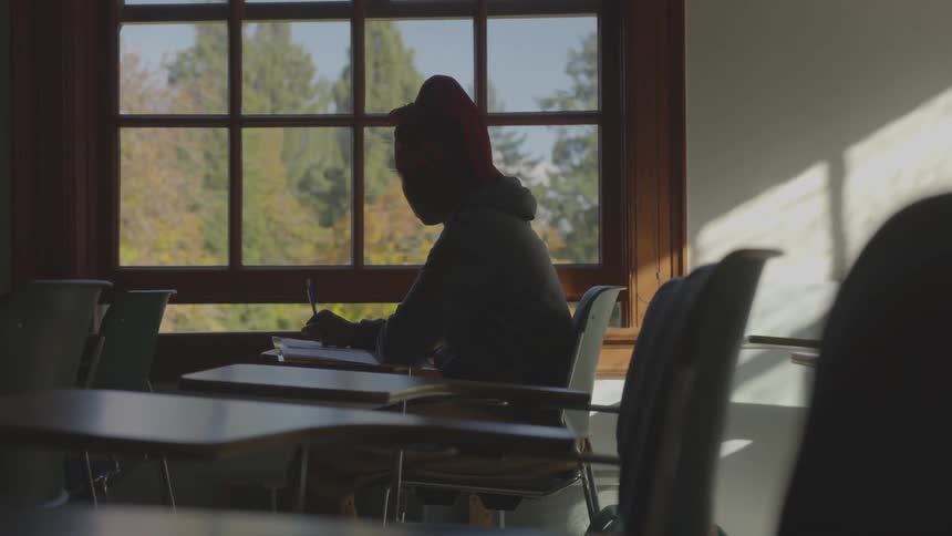 A woman sits alone in a dark classroom