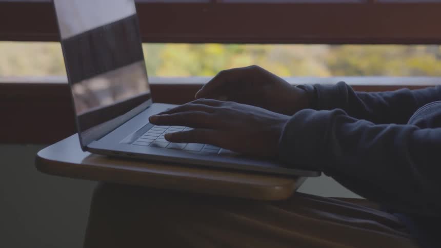 A person types on a laptop at a desk