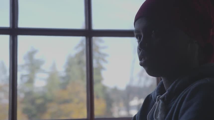 Black woman stands indoors in front of a window