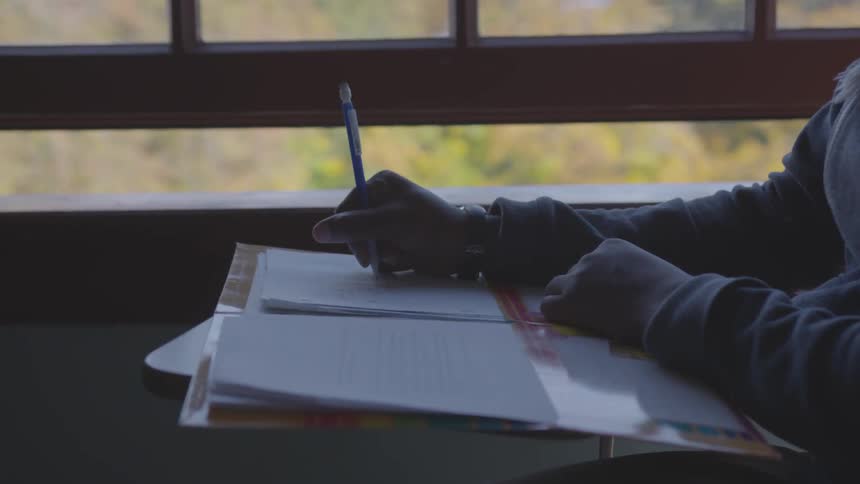 A girl writes in a notebook while sitting at a desk