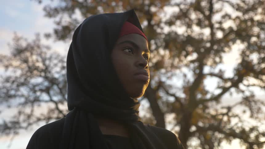 Young woman in a black burka sand under the trees