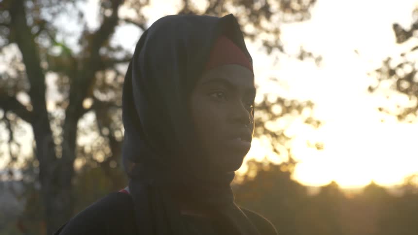 A black woman with a head covering stares into the distance