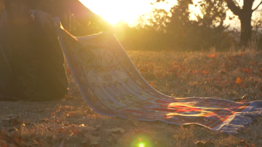 A black woman spreads a rug out on the ground