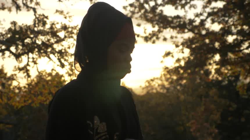 A woman talks while standing in a wooded area