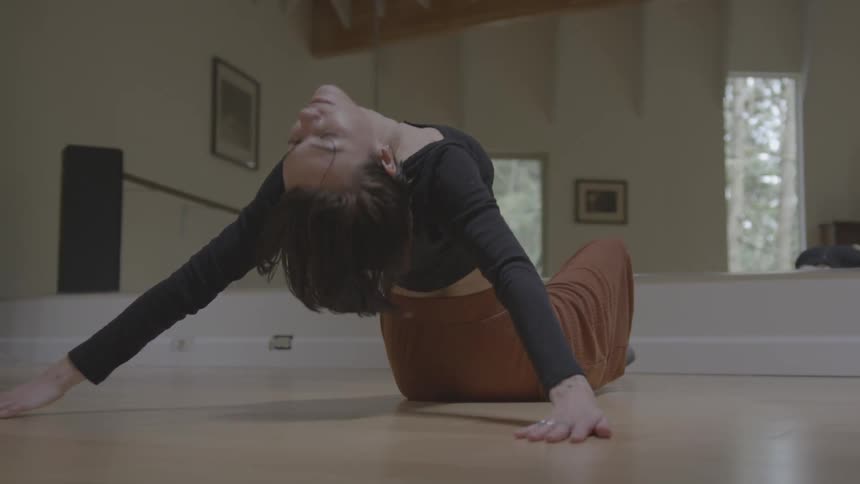 A woman in front of a mirror stretching