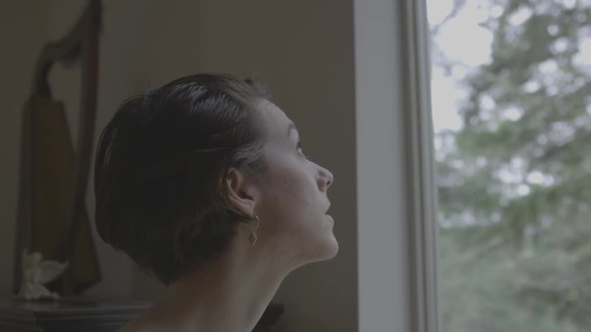 A woman with short brown hair looks out a window