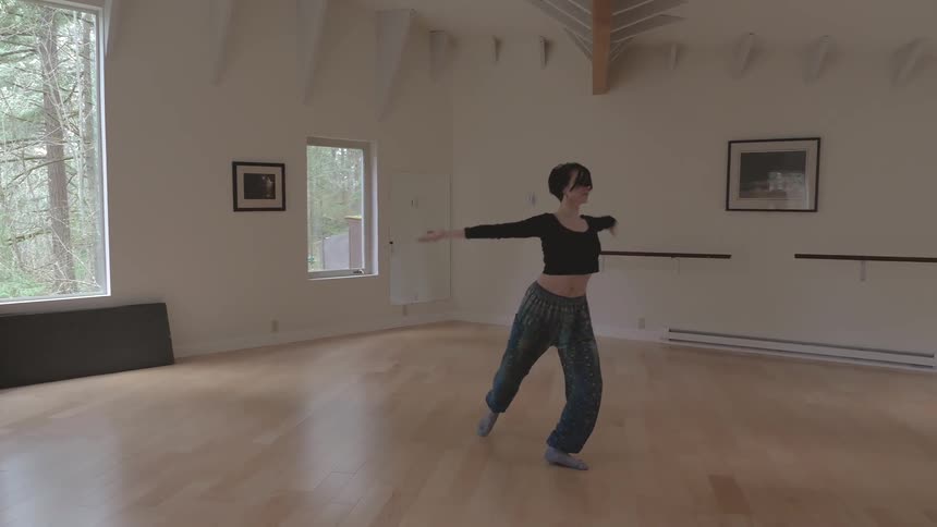 Woman dances alone in front of mirror in a room during daylight