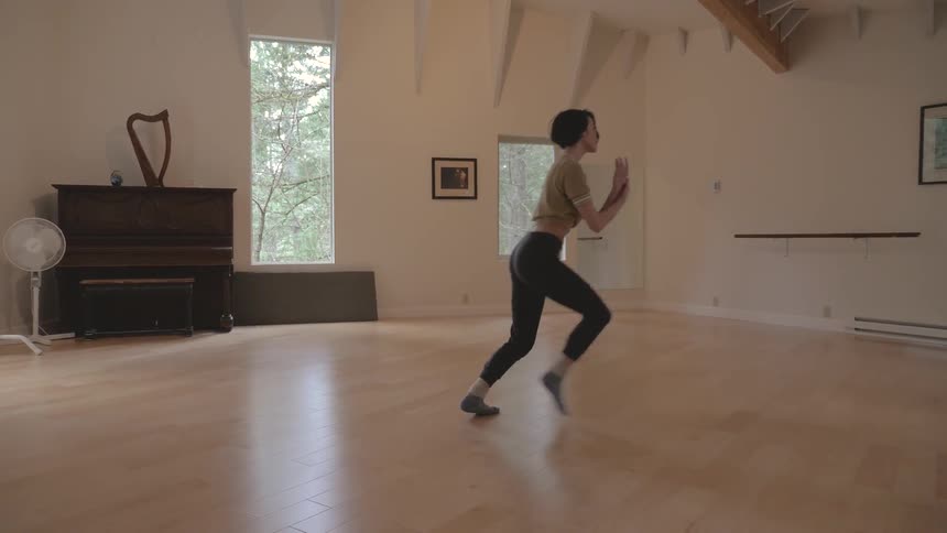 A woman practices dance moves in a studio
