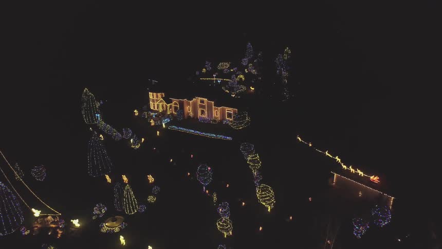 A home and yard are adorned with colored holiday lights