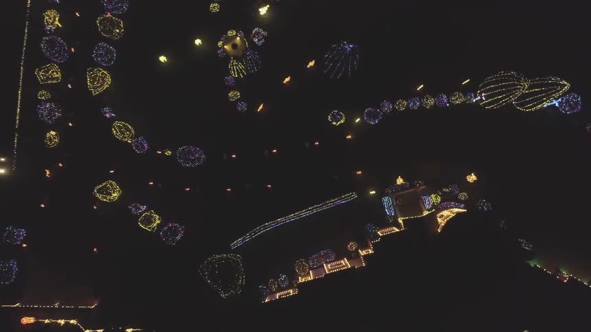 The camera flies above a neighborhood lit by Christmas lights
