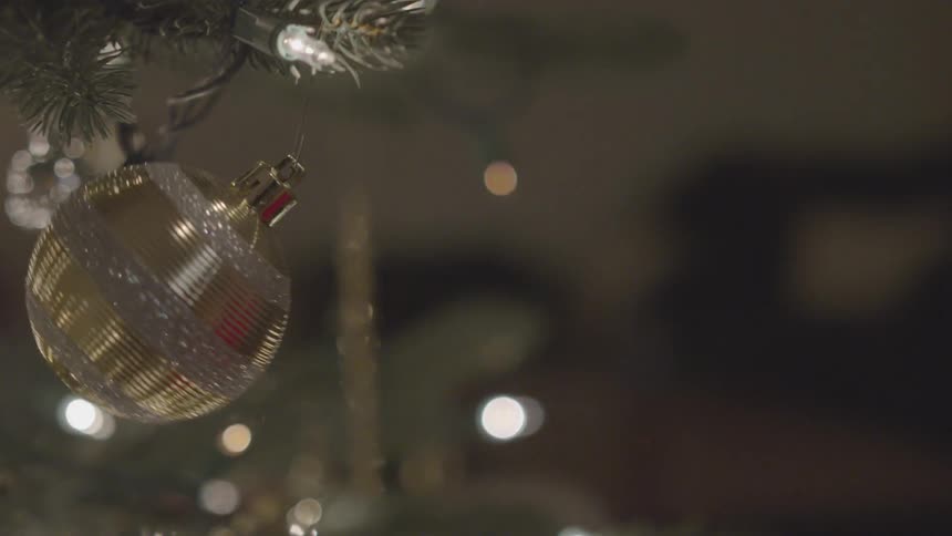A child tapping a holiday ornament hanging from a tree