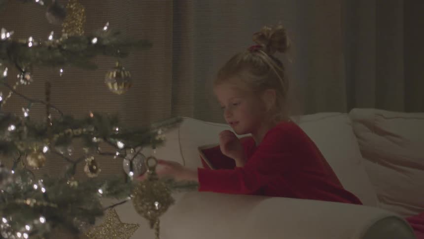 A girl touches an ornament on a christmas tree