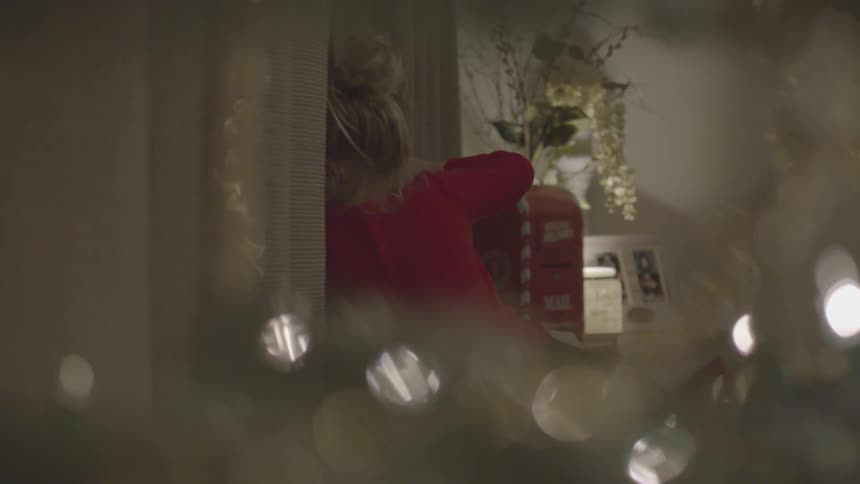 A young girl opening a curtain to look out a window