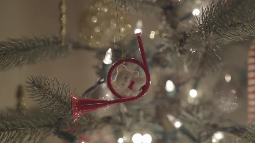 A closeup of a trumpet instrument ornament surrounded by holiday lights on a christmas tree