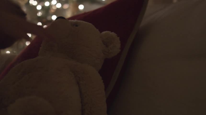 Child picks up a teddy bear from next to the cushion