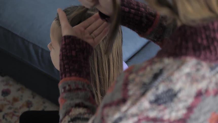 A mother begins to style her daughters hair