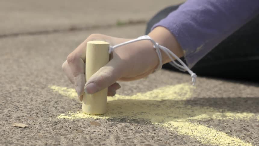 A person drawing a star on the sidewalk with chalk